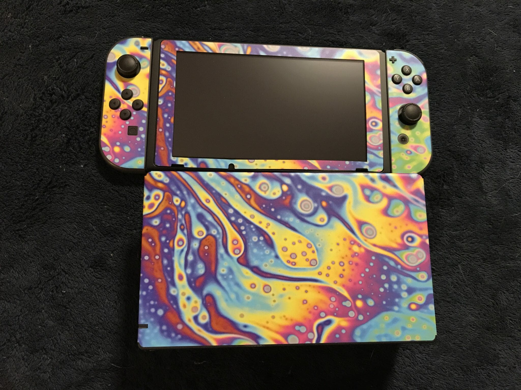 A Nintendo Switch with a very colorful soap-bubble vinyl skin.